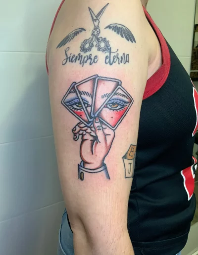 tijeras con alas, cuatro cartas con ojos y una mano que las sujeta